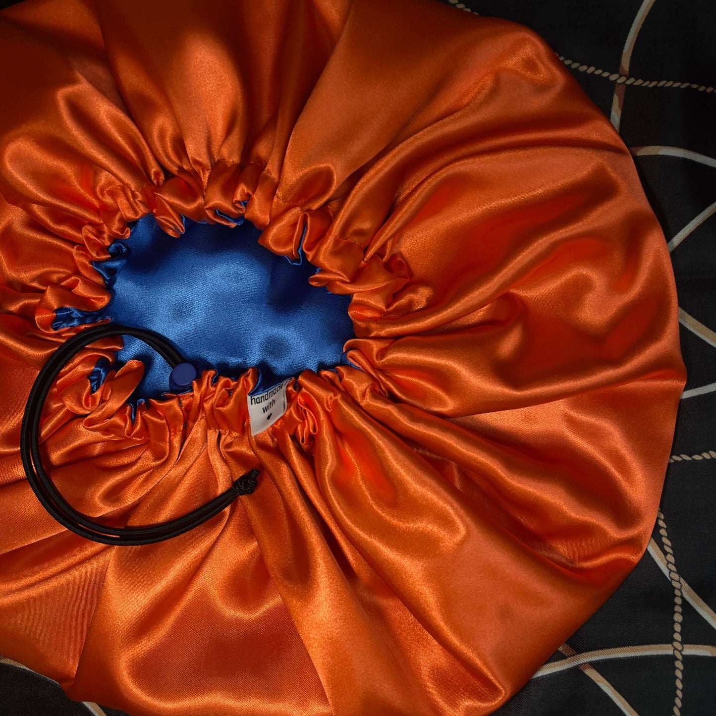 Orange drawstring bonnet with a blue interior on a dark textured surface
