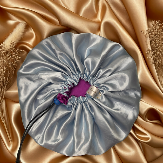 Silver drawstring bag with a purple tag on a gold satin background