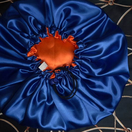 Blue satin hair bonnet with orange center on a dark background