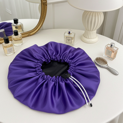 Purple drawstring bag on a white table with perfume bottles and a brush in the background