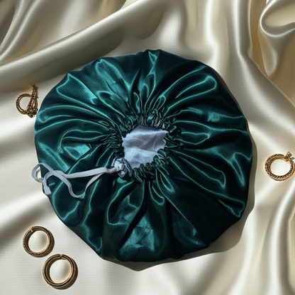 Green satin bonnet on a beige satin surface with gold hair ties.