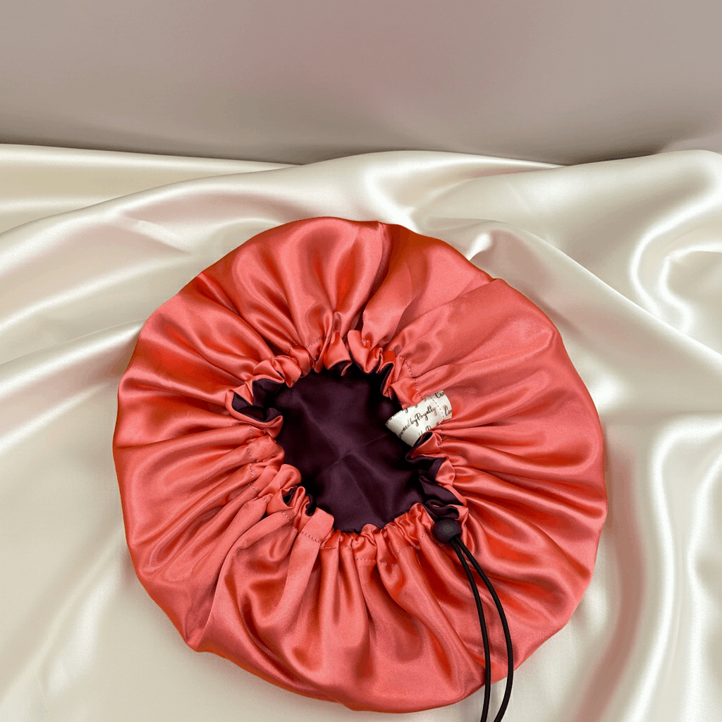coral drawstring bonnet on a white satin surface