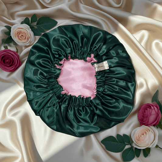 Green satin bonnet with pink interior on a beige fabric background with flowers