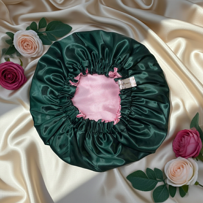Green satin bonnet with pink interior on a beige fabric background with flowers