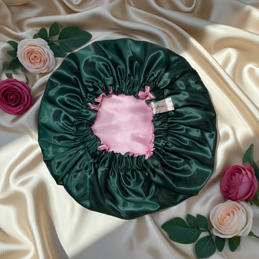 Green satin bonnet with pink interior on a beige fabric background with flowers