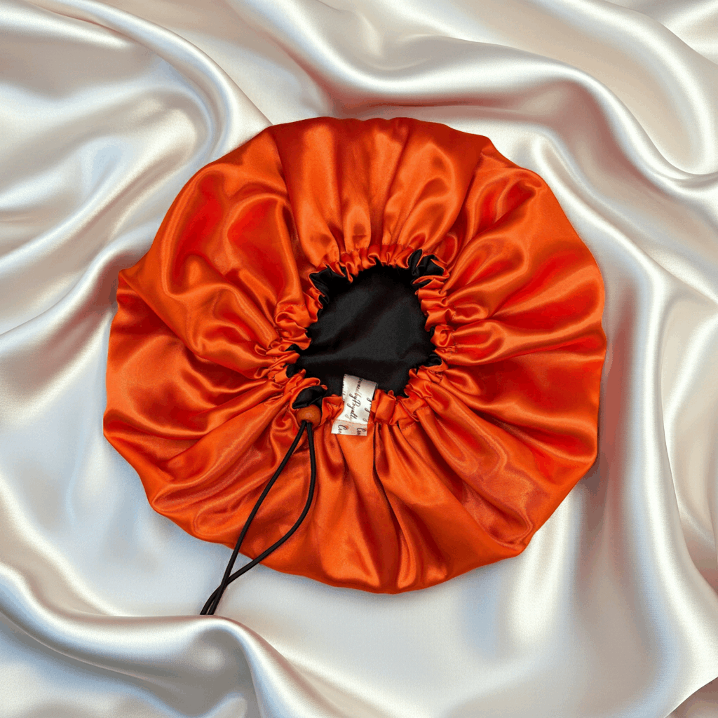 Orange drawstring bonnet on a white satin background
