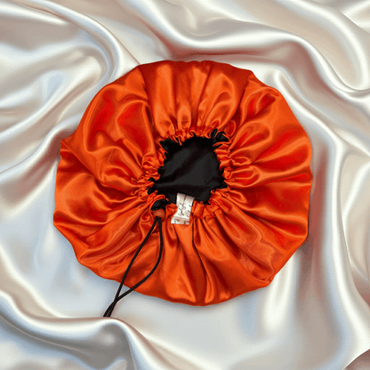 Orange drawstring bonnet on a white satin background