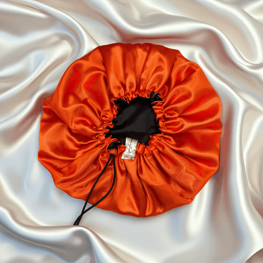 Orange drawstring bonnet on a white satin background