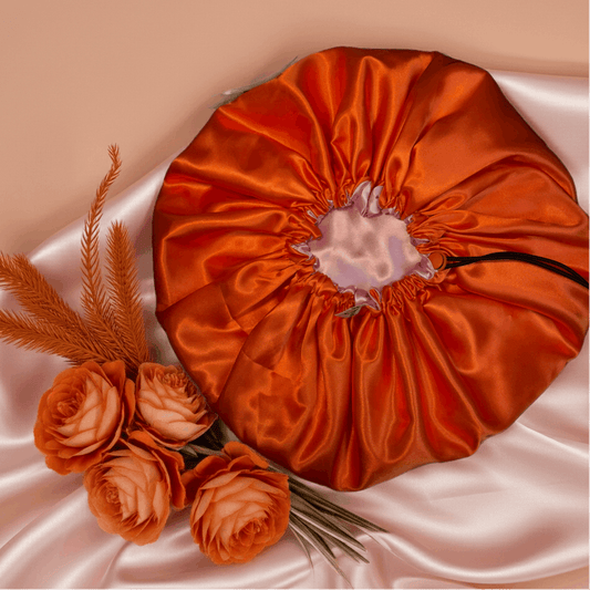 Orange satin drawstring bag with flowers on a beige background