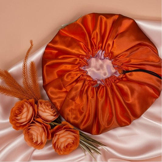 Orange satin drawstring bag with flowers on a beige background